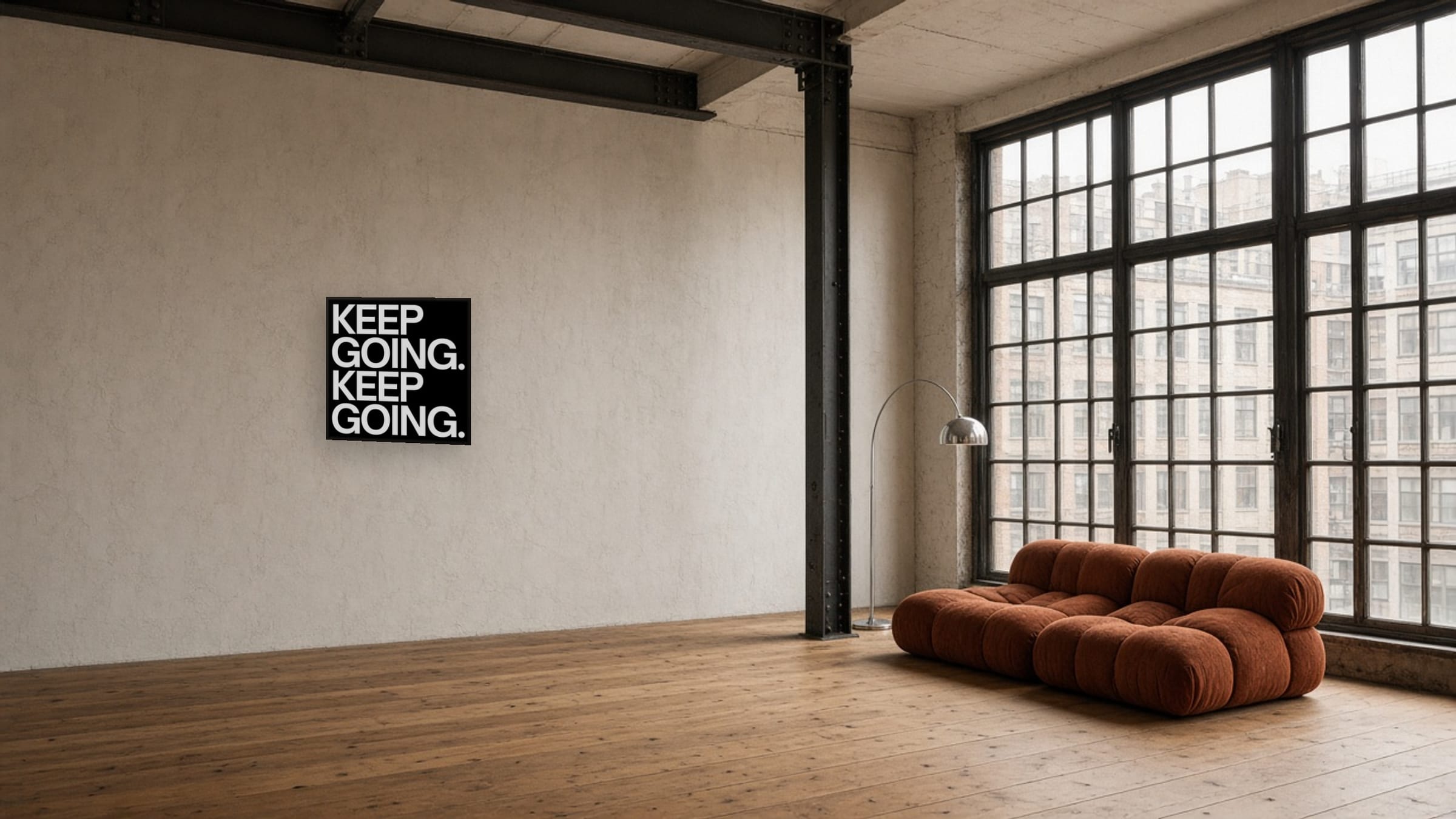Keep Going on framed canvas, white lettering on black, on a huge plaster wall in a New York loft with industrial steel windows.